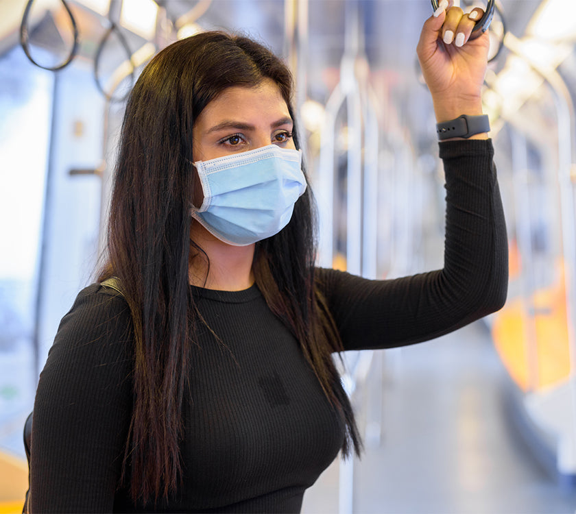 A young woman wearing a facemask on public transport